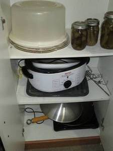 lot 165 image: Content of the pantry cabinet to include Tupperware style cake storage, roasters, wok plus other cook and bakeware