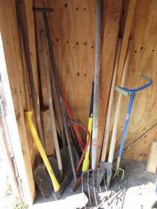 lot 246 image: Corner lot of assorted outdoor tools including shovels, lumber, post hole digger, fiberglass handled pick ax and maul, hacksaw and more