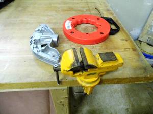 lot 32 image: Heavy duty clamp on bench vise, retractable metal measuring tape and pipe bender head