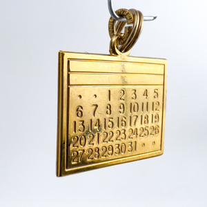 lot 46 image: Calendar (31 day) , Unknown Maker, Gold Plated Sterling Silver One-Part Stamped Charm.