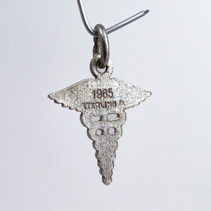 lot 110 image: Caduceus , Wells Charms  Sterling Silver One-Part Stamped Charm.
