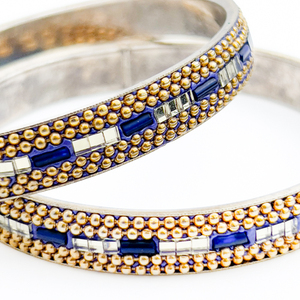 lot 107 image: Pair of Slip-On Bangle Bracelets. Enameled with a Central Row Of Beads Embedded Into Blue Enamel.