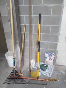 Two rakes, One broom and one small push broom, large floor squeejee, 40 LB bag of top soil, and open bag of easy sand.
