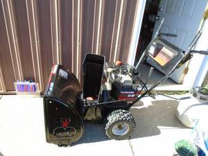 lot 104 image: Yard Machine 1024 snow blower with electric start. Used condition. Tested & works. As shown.