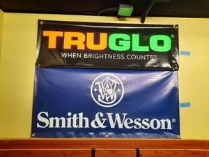 lot 1877 image: (2) Vinyl Banners Tru Glo measures 48 x 16 Smith & Wesson measures 72 x 36