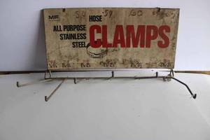lot 4 image: Massey Ferguson hose clamp display sign. Painted metal, needs cleaning, sign dimensions 17.5x8
