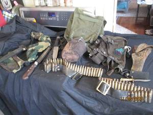 lot 40 image: Vintage Army gear including a canteen, utility belts, spent ammo casings with ammo belts and assorted fixed blade combat and boot knives