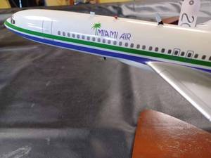 lot 21 image: Miami Air Die Cast  Metal Plane on a Wood and Metal Stand, Plane Measures 18.5-inches Long, 13-inches Wide Wing Tip to Wing Tip, and 9.25-inches from
