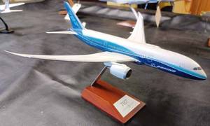 lot 24 image: Metal 787 Dream Liner on a Wood and Metal Stand, Plane Measures 11.5-inches Long, 12-inches Wide Wing Tip to Wing Tip, and 7.25-inches from the Base