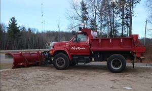 A 1997 FORD GAS DUMP TRUCK WITH A PLOW PLUS SALTING ATTACHMENT.