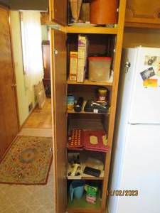 Content of cabinet left of fridge including small kitchen helpers and other supplies