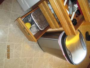 Ninestars Stainless steel motion sensor garbage can along with the content of drawers to the right of stove including measuring Spoons and cups as well as other cooking and baking utensils and supplies