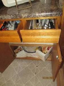 Content of backside drawes and lower cupboard containing a serving platter, turkey shaped gravy boat with salt and pepper shakers, plastic Tupperware style tv trays, household maintenance tools and supplies plus more