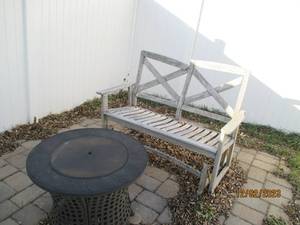 Shabby Chic style wood glider bench in need of tlc paired with a metal framed gas fire pit