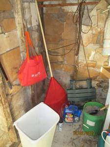 Leaf rake, small outdoor folding table, garbage can and 5-gallon bucket of pea rock