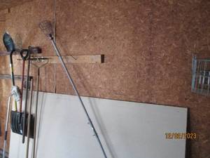Long handled yard tools, shovels and cage style fruit picker plus a slab of sheetrock
