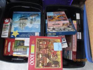 lot 54 image: Nice assortment of jigsaw puzzles in a variety of difficulty levels. (If any pieced were to be missing, it seems to be noted) filled between (2) covered storage totes