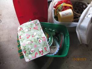 lot 58 image: (2) Covered Storage Totes. One is filled with an assortment of holiday place settings and decor while the other contains an assortment of baskets and home decor