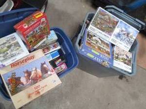 lot 62 image: (2) Covered Storage Totes filled with a nice assortment of jigsaw puzzles in a variety of difficulty levels. (If any pieced were to be missing, it seems to be noted)