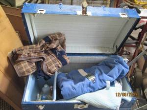 lot 75 image: Vintage Blue painted wood Storage trunk with metal trim and accents as well as a thick leather handle on each end. Truck contains misc bedding, personal care and 1st aid type supplies 3218.521.5