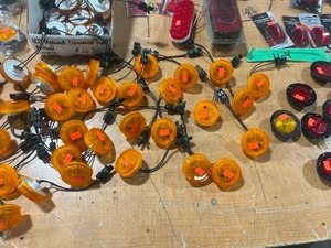 TABLE FULL OF SEMI-TRUCK TRAILER LIGHTS AND HOLDERS