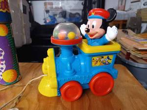 lot 83 image: Lot of Vintage Toys including a 2000 Cube It Up Electronic Talking Toy Game by Toy Biz - Needs Batteries, Disney Mickey Mouse Plastic Locomotive Pull Toy, Fisher Price Music Box Pocket Radio