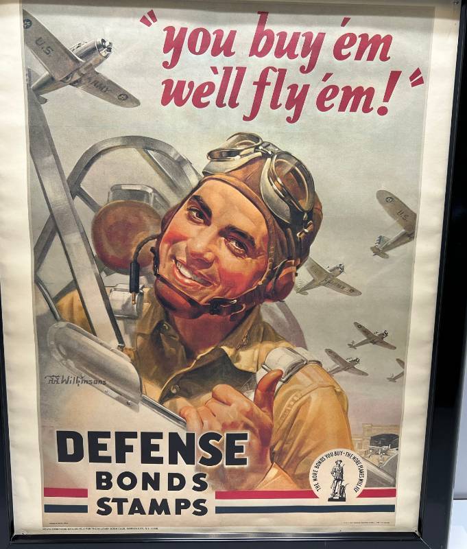 lot 210 image: Framed 1960s Wilkinsons Repro You Buy em We Fly Em Defense Bond Stamps Military Book CLub Poster 18 x 22 (Pinholes Present In Corners)