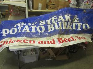 lot 177 image: (F-2) Taco Johns New Steak & Potato Burrito Banner Sign Approx 8ft x 3ft - Dirty  Needs Cleaning