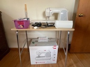 lot 2 image: Singer Athena Sewing Machine with sewing table and vintage dress hemmer and misc. supplies