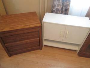 White wall cabinet with 2-doors and lower tier open shelf along with a wood grain style wood 2-drawer night stand
