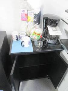 lot 132 image: Black wood 2-door cabinet used as coffee station PLUS coffee maker and supplies shown