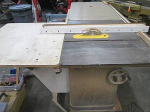 Massive Delta Unisaw unit (must bring help to removal due to size and weight) includes dust collection tube from unit to vent near ceiling