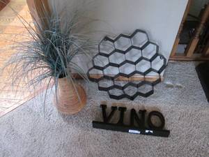 lot 19 image: Honeycomb style tin wall decor and faux foliage weeping from its Wicker vase accompanied by a wood mantel sign