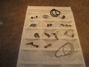 lot 40 image: Compartmentalized fabric hanging organizer containing pierced earrings and necklaces