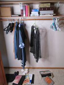 lot 57 image: Content of spare bedroom closet consisting of womens dress attire, photo albums and frames, weights and home decor