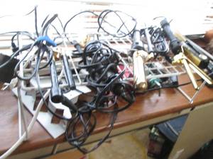 lot 80 image: Coated Wire riser with a variety of curling and flat irons as well as some blow dryers and other Misc
