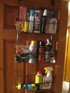 lot 96 image: Metal over-the-door hanging shelf full of household cleaners, sealants, lubes and other supplies