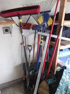 lot 114 image: Corner caddy filled with yard tools, brooms and even a clamp