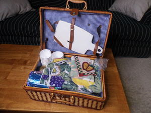 lot 177 image: Wicker Rattan picnic basket full of table coverings and disposable dinnerware