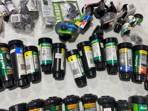 TABLE FULL OF RAINBIRD SPRINKLER HEADS & ATTACHMENTS