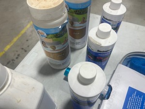 TABLE FULL OF POOL CHEMICALS, & LEAF RAKE
