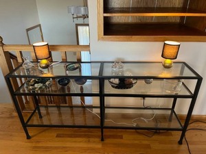 lot 7 image: Two-Tiered Glass Console Table (65 x 14 x 30.5) with an Assortment of Decorative Pieces