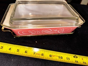 lot 129 image: Rare PYREX Pink Swirl Scroll Casserole with Lid and Original Cradle Stand (Small chips on cover)