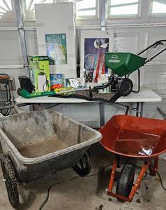 lot GAR25 image: Gardeners Delight- Garden Cart, Wheelbarow, Weed Eater, Plant Stand 2 gal Sprayer, deck box, fertilizer, planter, plant clips, american flag