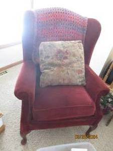lot 21 image: Beautiful burgundy Upholstered Wingback style chair with floral accent pillow and afghan