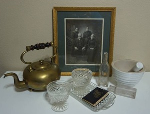 lot 61 image: Vintage Stoneware Typhoon England Pestle and Mortar, Squat Brass Teapot Applied Scrolled Brass Handle Brackets Boldly Turned Wood Handle, Clear Glass TablewareBottles Viginia Slims Little Black Book, Historical Framed Family Photo...