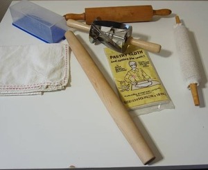lot 69 image: A Whole Lot of Baking Goods...Vintage Cadie Pastry Cloth and Rolling Pin Cover Set Ends Sticking 18 X 18, Stainless Steel Croissant Cutter Rolling Pin, Wood Rolling Pins and More