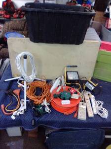 Large lot of extension cords, multi-plugs, surge protectors, lights. Includes tote with lid