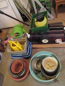 lot 128 image: Scotts speedy green spreader, 2 gallon chemical sprayer, watering cans and assortment of planters plus misc rugs