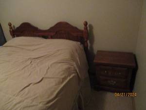 lot 22 image: Decorative Wood Headboard and metal bedframe accompanied by a petite 2-drawer wooden nightstand